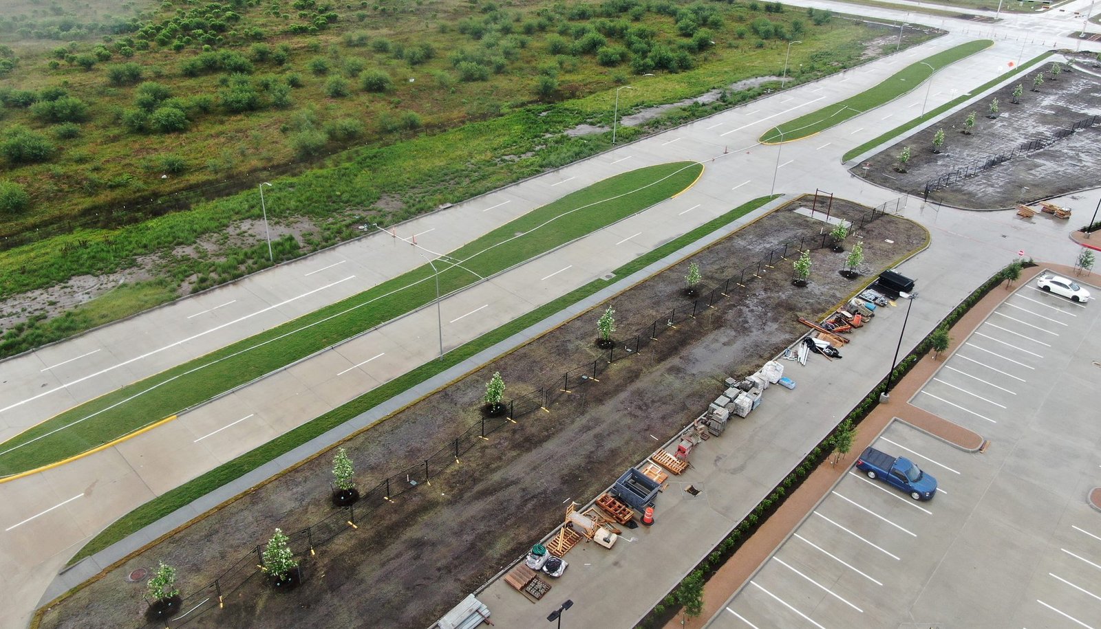 Aerial view of an active Greater Houston construction site with new roadways, landscaping, and staged building materials