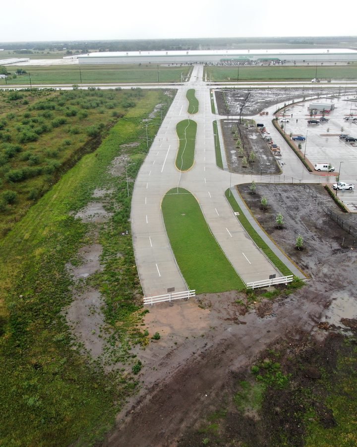 Aerial view of new commercial site infrastructure: entry roads, parking, and landscaping under construction
