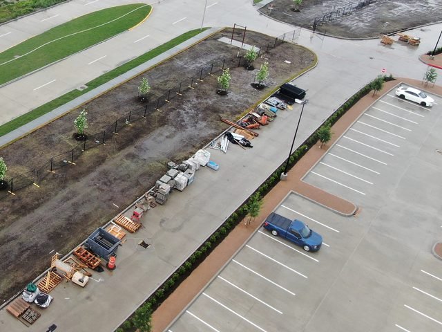 Construction materials staged beside a newly paved parking area